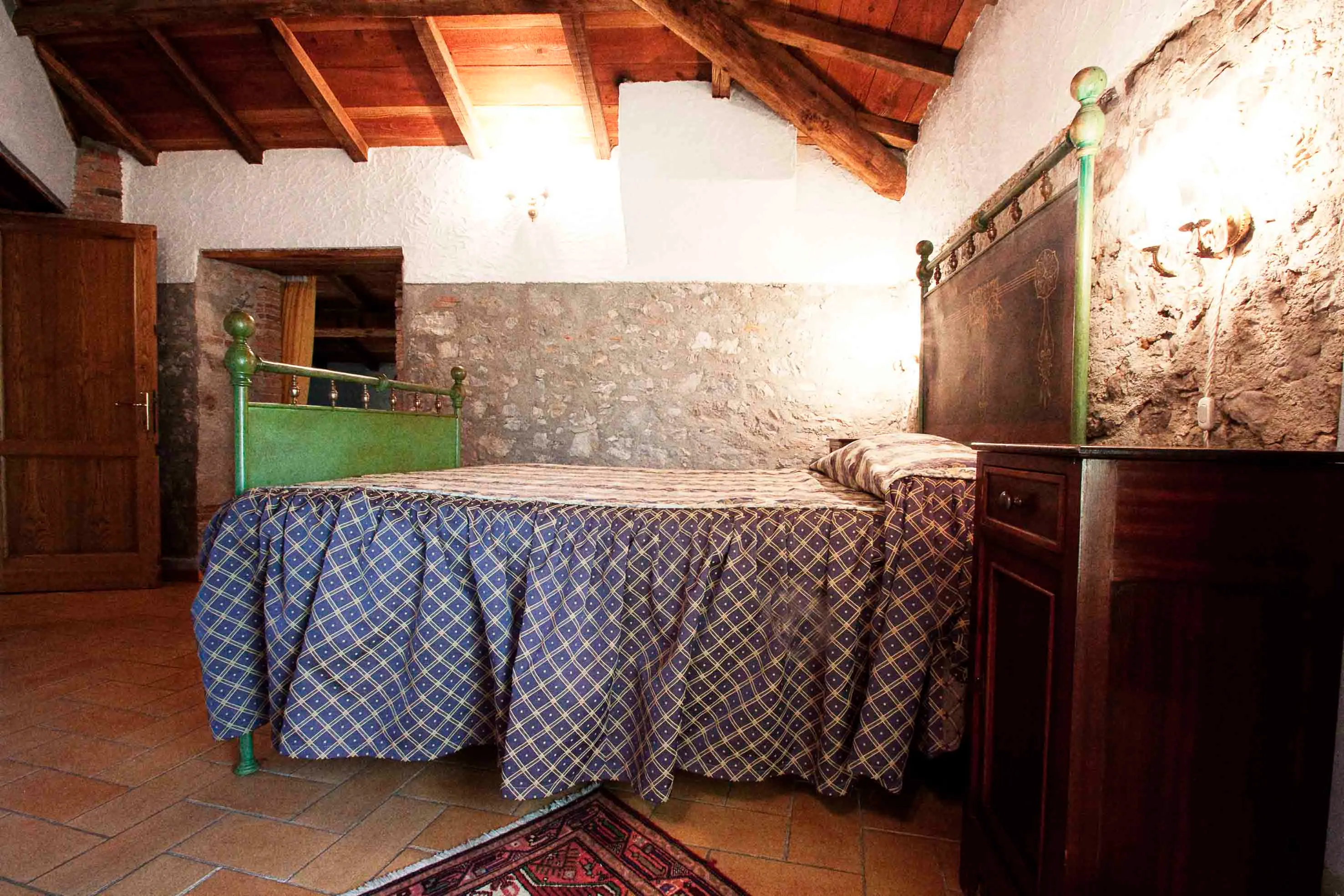 Camera della Sandri con letto matrimoniale e muro in pietra