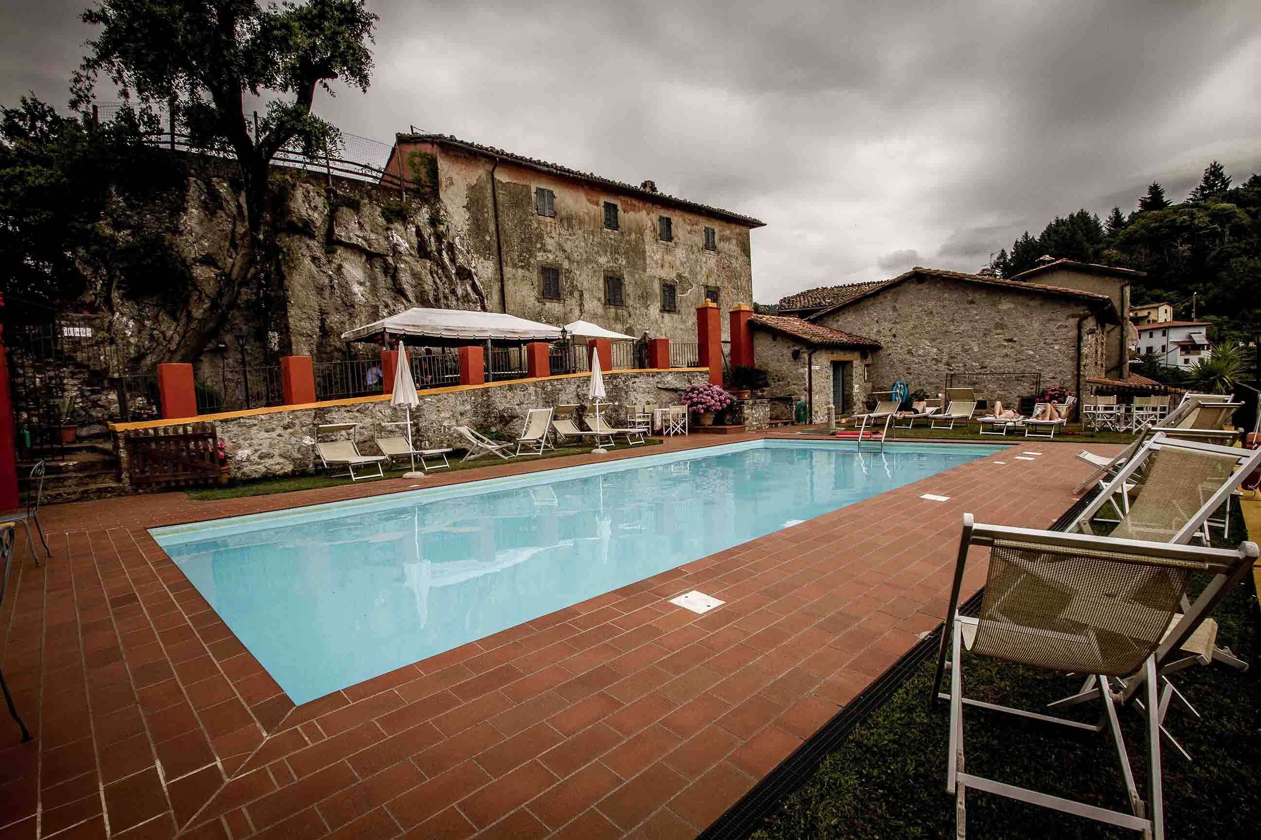 Il casale in pietra dei Cerretelli sullo sperone di roccia, con la piscina e i lettini in primo piano